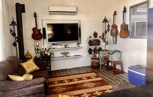 Wohnzimmer mit Fernseher, Schlafsofa, Eismaschine, Kühlschrank und Gitarren