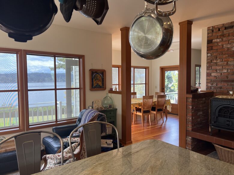 View from kitchen of seating area, woodstove, dining area