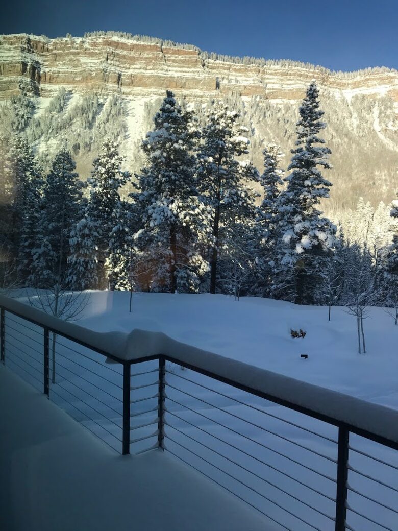 Deck with views of snow covered cliffs and trees.