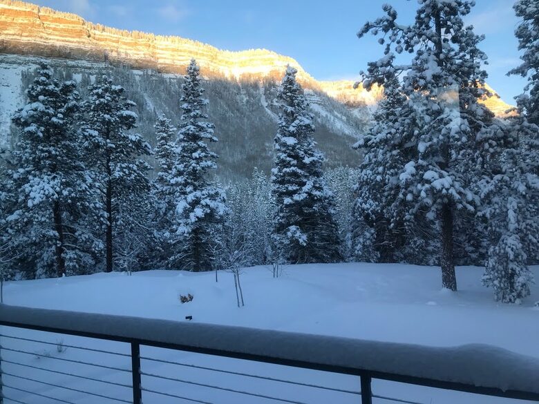 Deck with views of snow covered cliffs and trees.