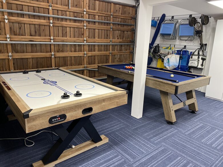 Gaming area adjacent to sports/beach accessories in garage.