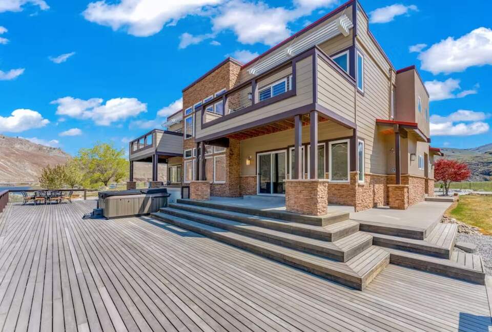 Expansive back deck with large hot tub, outdoor dining area, firepit.