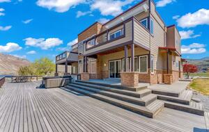 Expansive back deck with large hot tub, outdoor dining area, firepit.