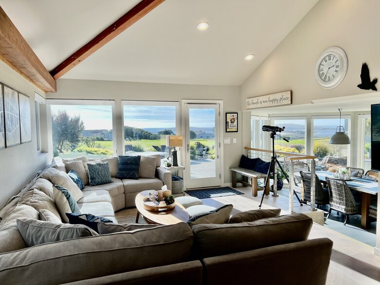 Living room and dining room with fairway and ocean views beyond.