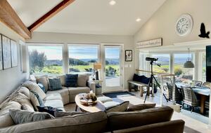 Living room and dining room with fairway and ocean views beyond.
