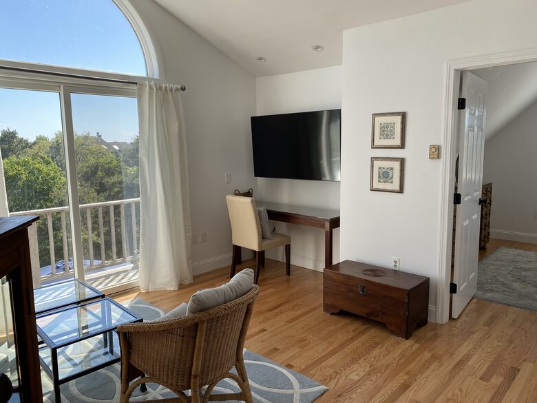Primary bedroom suite with balcony tv, desk and living room area