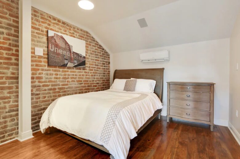 Bedroom 2 features a cozy bed, exposed brick accent wall