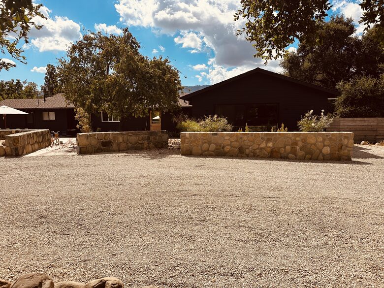 Black modern ranch-style with stone walls around front patio