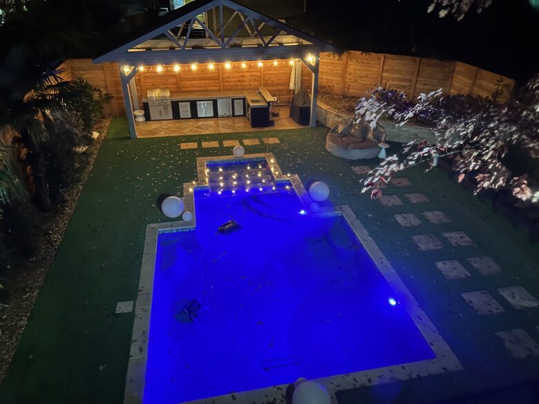 Night view from sunroom of pool deck and outdoor kitchen