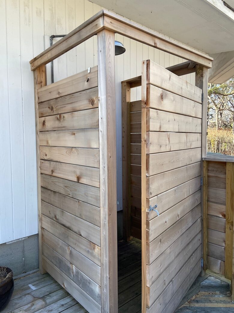 Outdoor shower next to pool has views of the treetops.