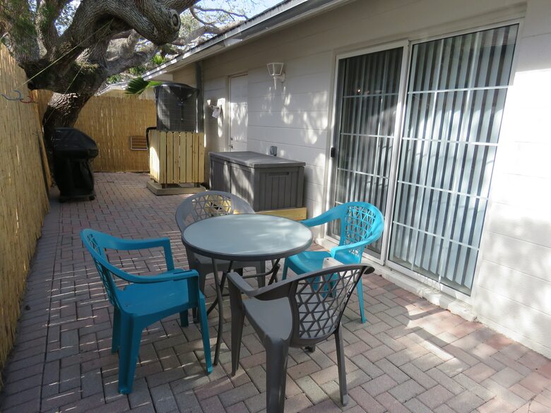 Private backyard with table, chairs, beach box and grill.