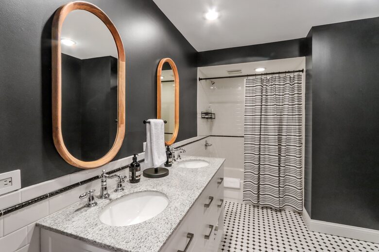 First floor double vanity sinks, toilet, and shower/tub combo